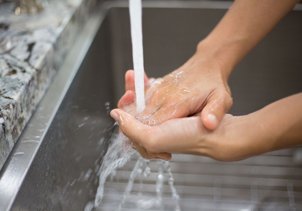 person washing hands in sink